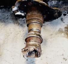 Drive axle bolt-on spindle before replacement, showing corroded and damaged bearing journals